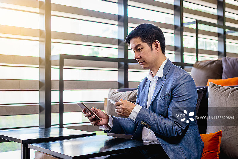 亚洲商务男士在办公室使用手机和信用卡支付图片素材
