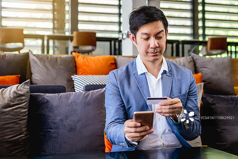 亚洲商务男士在办公室使用手机和信用卡支付图片素材