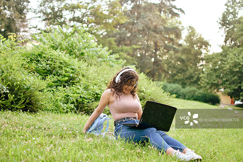 女孩用笔记本电脑听音乐和下载音乐图片素材