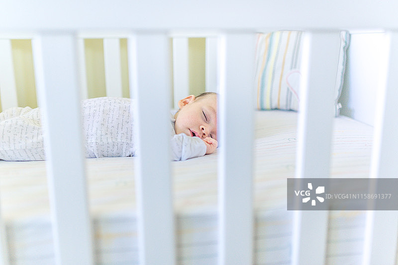 在婴儿床里睡觉的可爱婴儿图片素材
