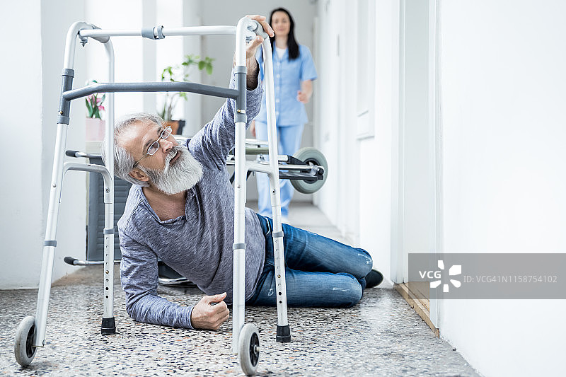 护士帮助从轮椅上摔倒后站起来的老年男子图片素材