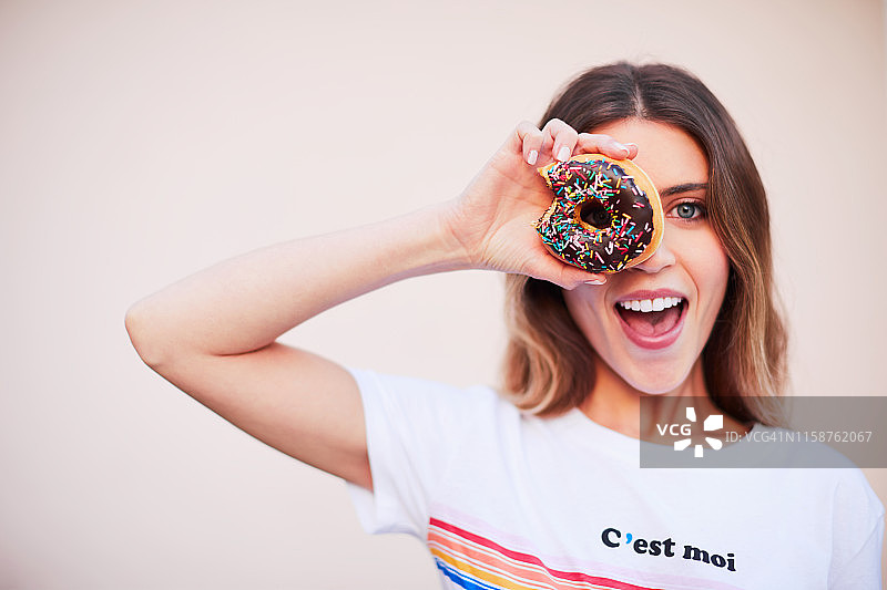 年轻漂亮的白人千禧一代为社交媒体摆姿势。拿着一个甜甜圈。图片素材