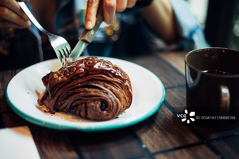 在咖啡馆吃巧克力羊角面包的女人图片素材