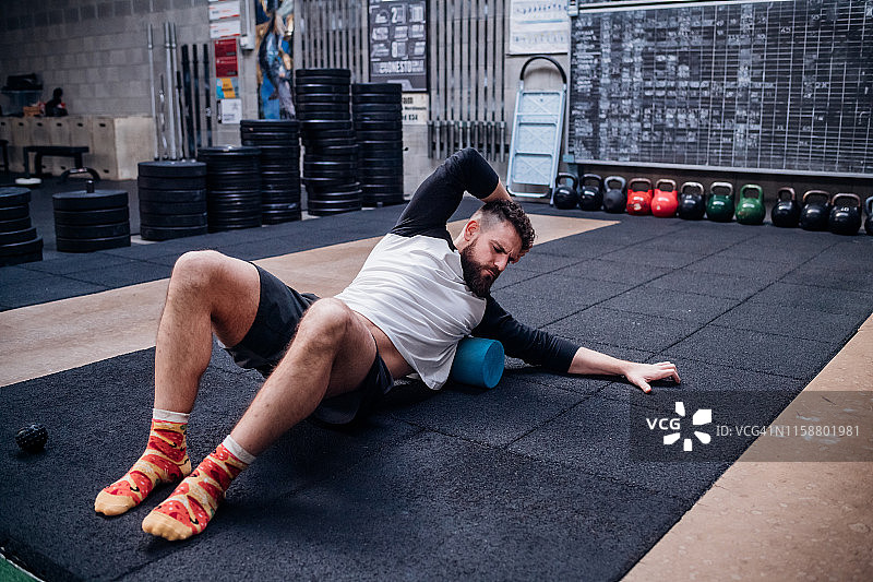 年轻男人在健身房用泡沫轴按摩身体图片素材