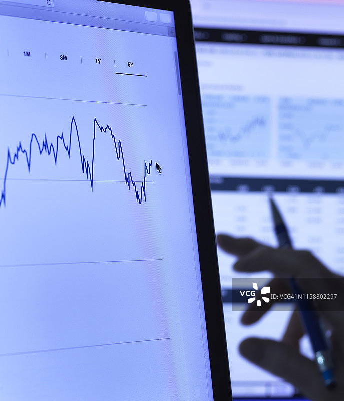 金融服务：股票分析师在电脑上研究公司股价数据（特写）图片素材