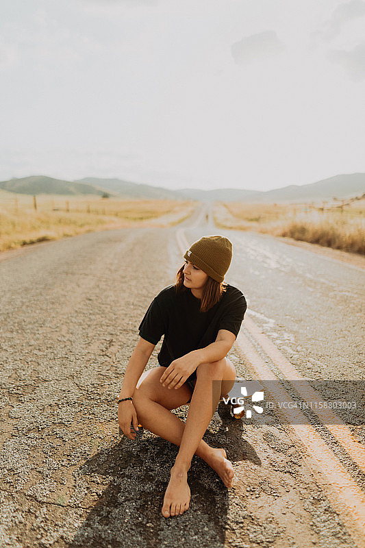 年轻女滑板手坐乡村小路上图片素材