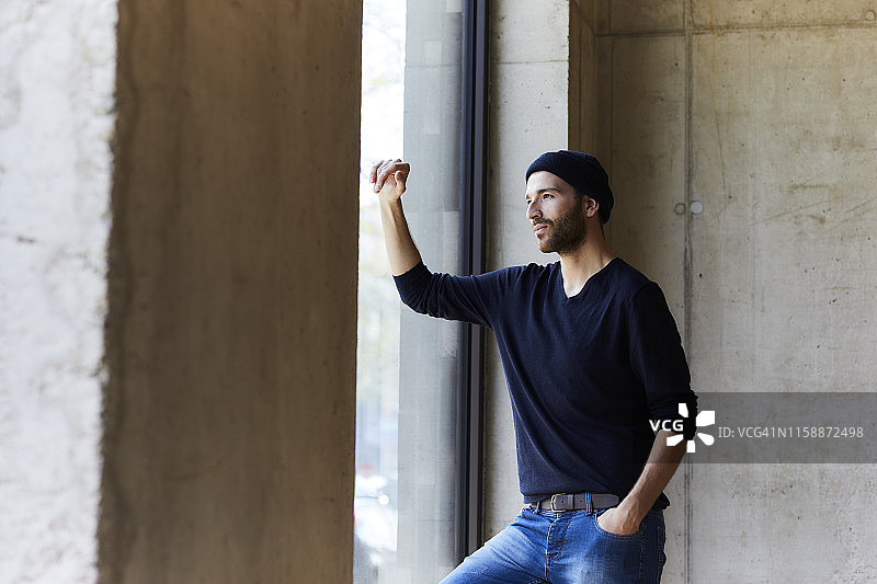 戴着无檐小便帽，向窗外看的年轻男子图片素材