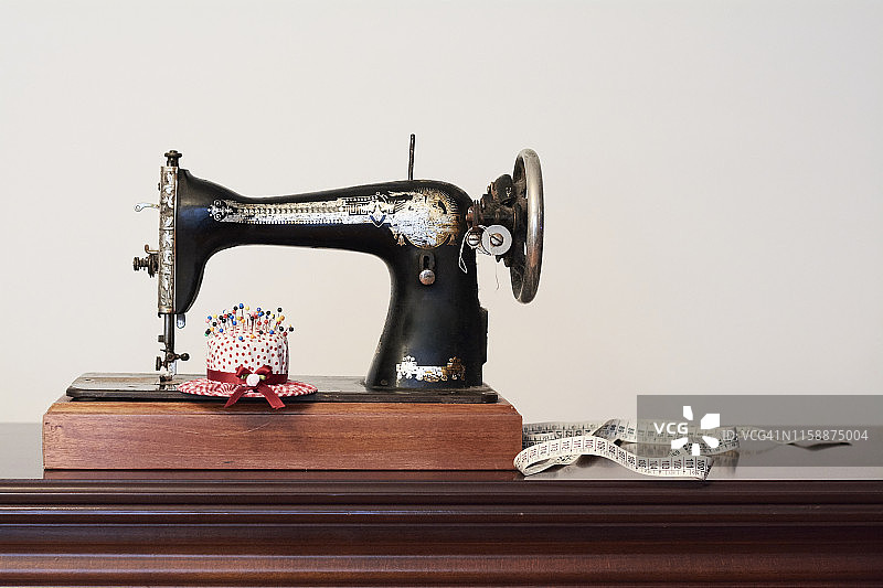 带卷尺和帽子形针垫的旧式缝纫机图片素材