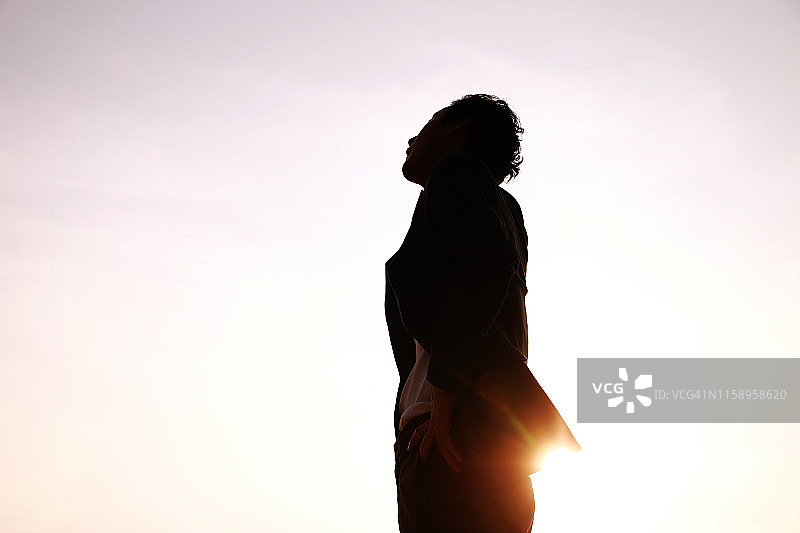 在日落时抬头仰望天空的商人剪影图片素材