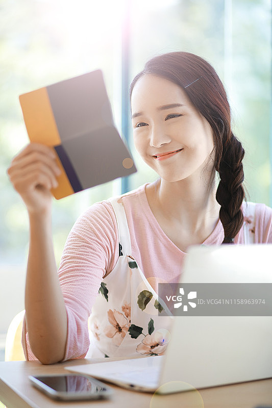 年轻女人用存折进行网上银行转账图片素材