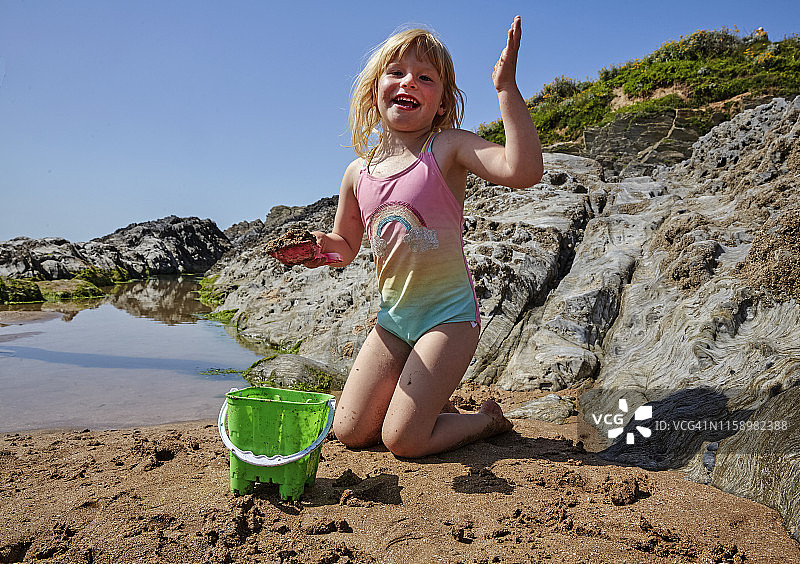 女孩在沙滩泳池前堆沙堡图片素材