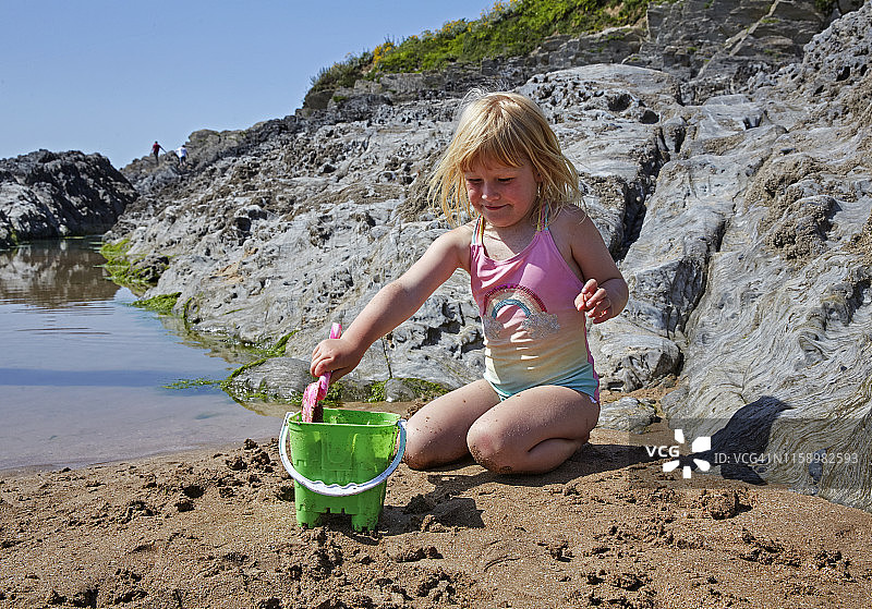 女孩在德文郡泳池旁堆沙堡图片素材