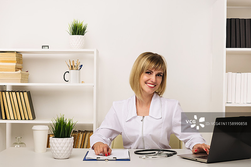 友好的女医生在办公室办公桌前工作图片素材