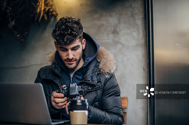 英俊的摄影师正在看相机上的照片图片素材