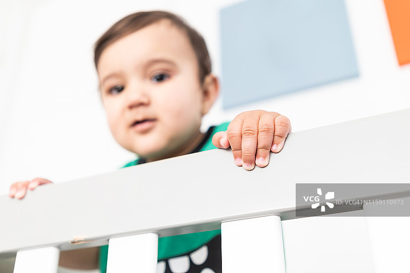 婴儿站立并扶着婴儿床栏杆的手部特写图片素材
