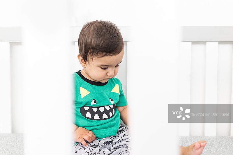 宝宝坐在婴儿床护栏后图片素材