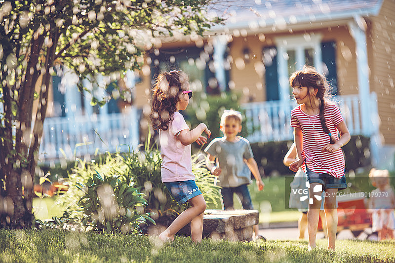 孩子们在花园里玩洒水器图片素材