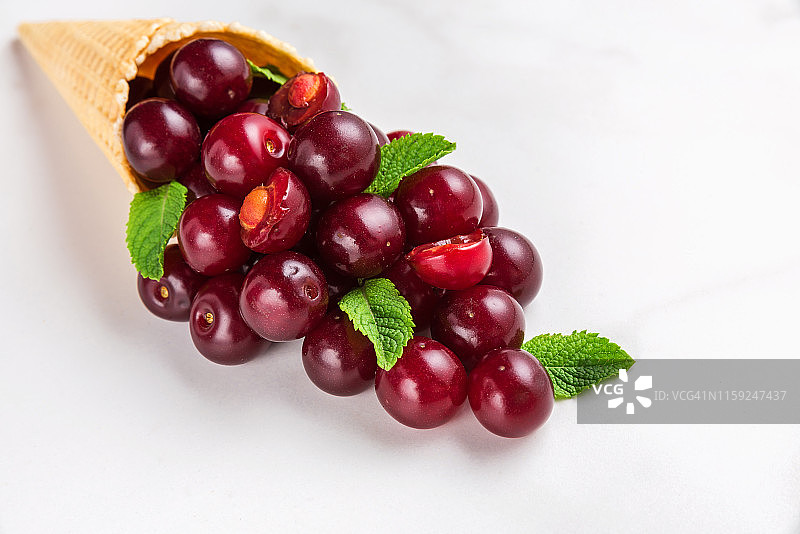 白色大理石背景上的华夫饼甜筒夏日樱桃薄荷浆果美食概念图片素材