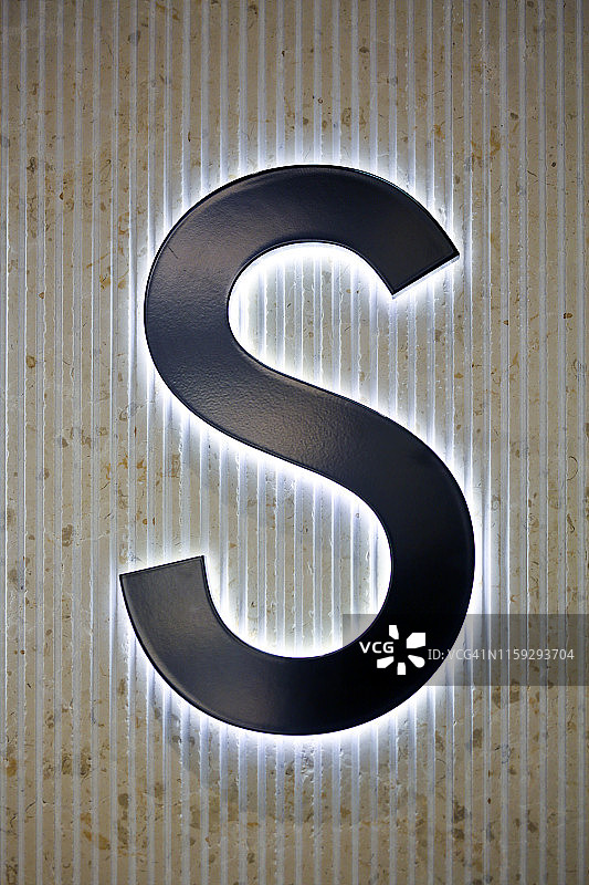 石墙上发光的字母“S”图片素材