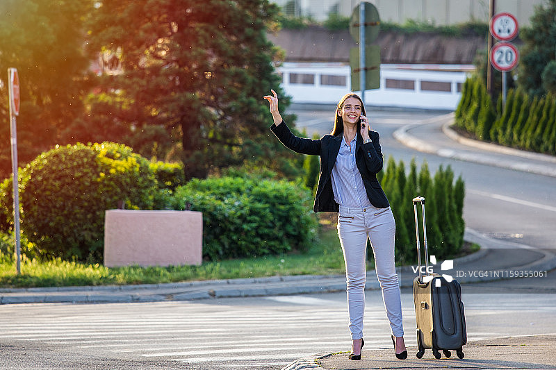 微笑的年轻女人试图拦出租车，正在呼叫出租车图片素材