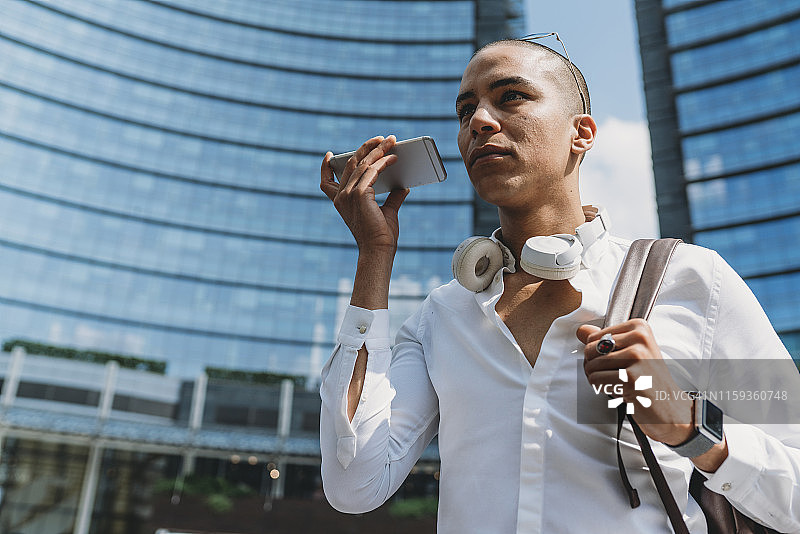 在城市里用智能手机听语音邮件的年轻商务男士图片素材