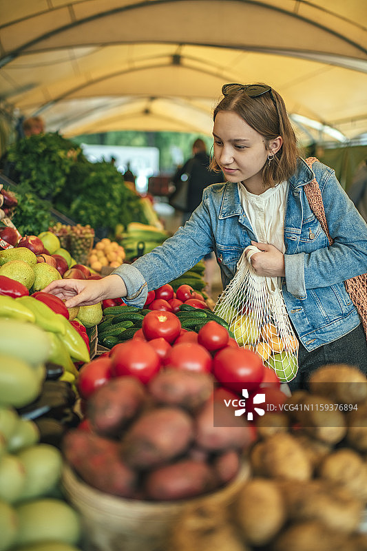 在农贸市场挑选蔬菜水果的年轻女孩图片素材