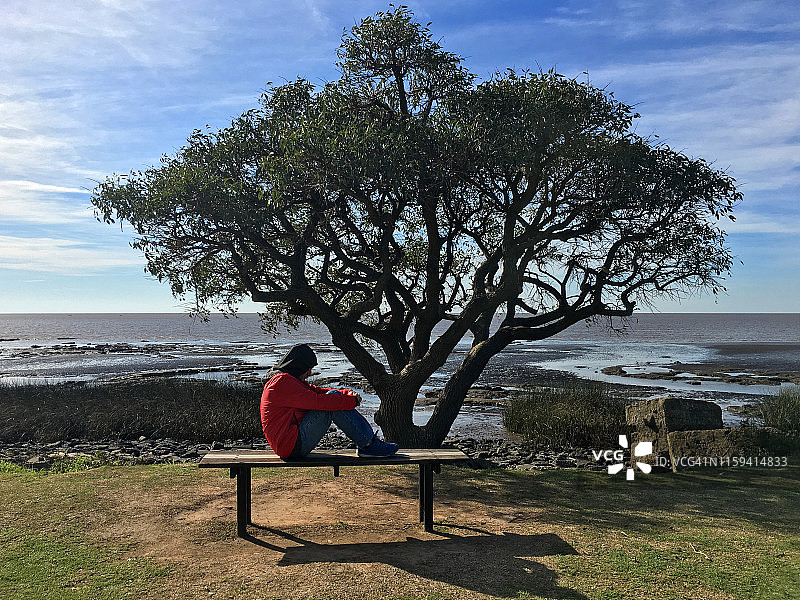 男人坐在河边的公园长椅上图片素材