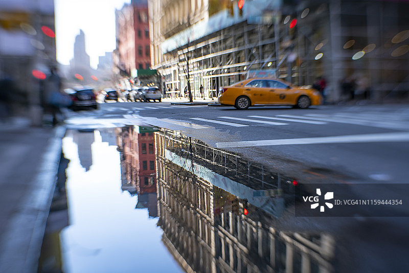 2018年12月23日，纽约曼哈顿百老汇沿街的成排建筑倒映在街道的水坑中图片素材