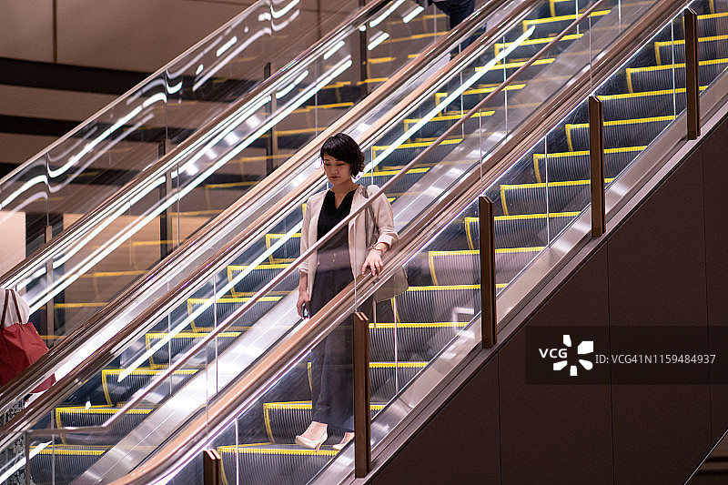 下班后走下自动扶梯的年轻女商人图片素材