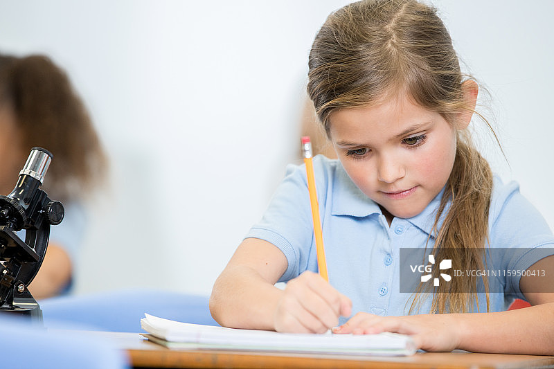 小学生在私立学校的STEM课堂上用铅笔写字图片素材