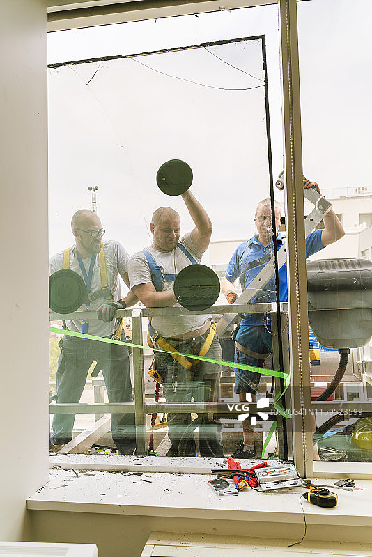 蓝领工人团队更换办公楼破损窗户图片素材