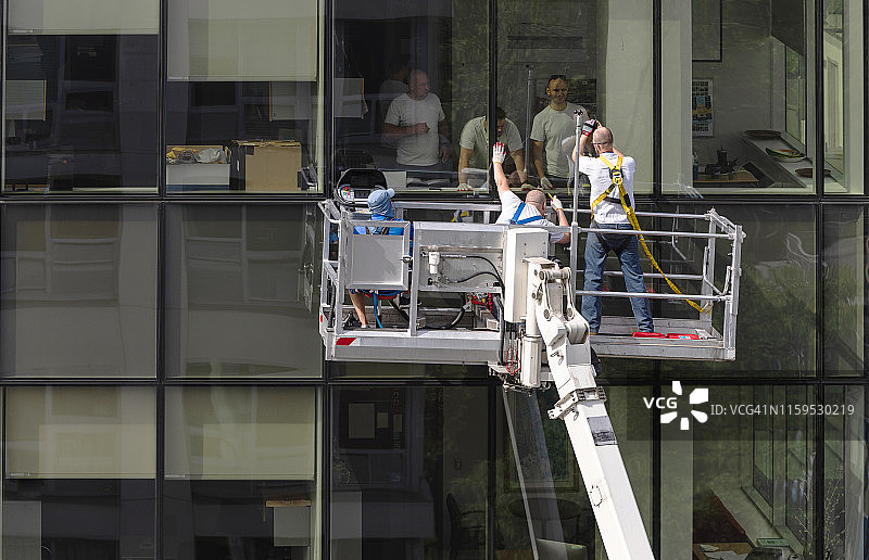 高空作业：两组工人在办公楼玻璃幕墙上工作图片素材
