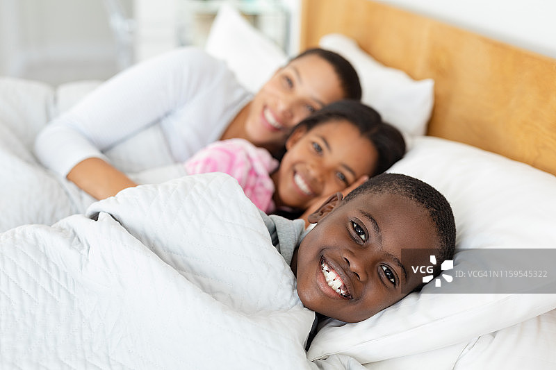 母亲和孩子们在家里的卧室里一起在床上放松图片素材