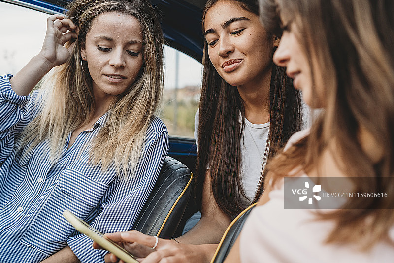 朋友们在车内使用智能手机图片素材