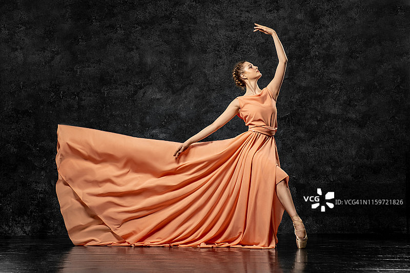 芭蕾舞女演员：身穿桃色长裙、脚穿缎带足尖鞋的年轻舞者，表演优雅的舞蹈动作，展现优美的古典芭蕾，芭蕾舞工作室广告，立体照片图片素材