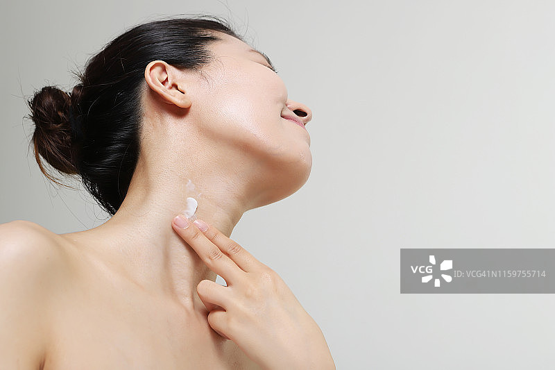 年轻女子在脖子上涂抹润肤霜图片素材