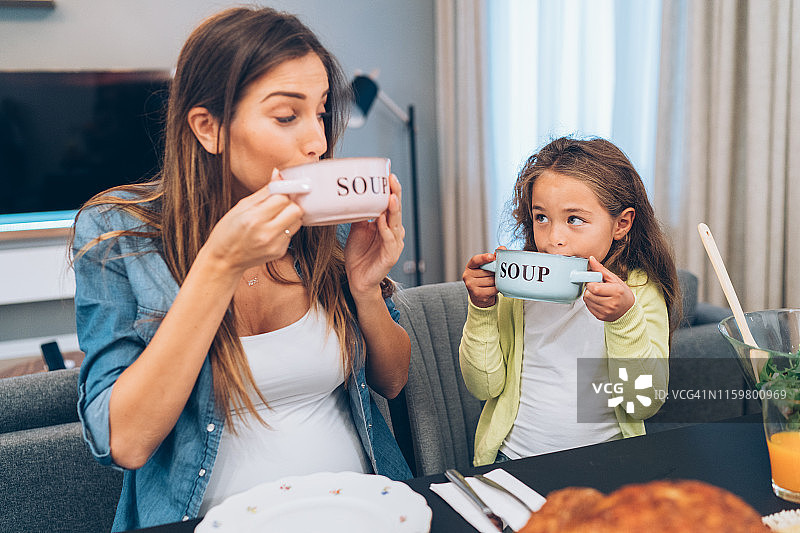 母亲和可爱的女儿享用汤和烤火鸡图片素材