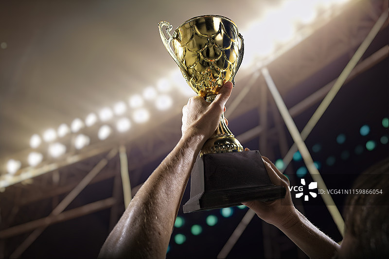 运动员在体育场高举奖杯图片素材