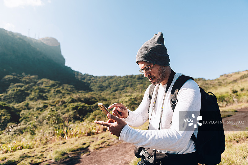 中年摄影师在户外使用手机图片素材