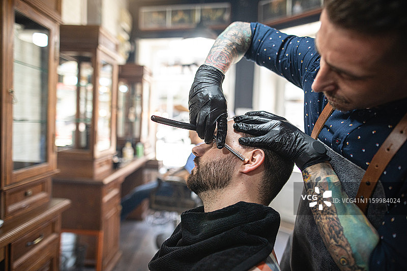 技术精湛的理发师为顾客刮胡子图片素材