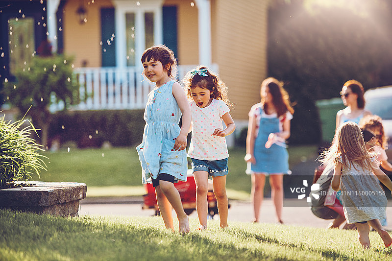孩子们在花园里玩洒水器图片素材