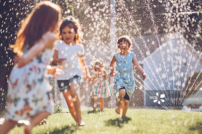 孩子们在花园里玩洒水器图片素材