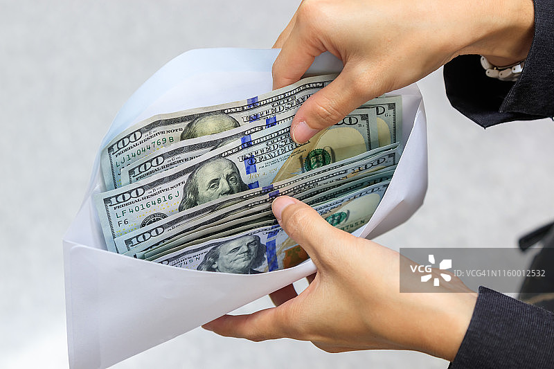 白色信封里的美元纸币和商业女性的手。信封里的美元。女性用现金支付。兑换概念图片素材