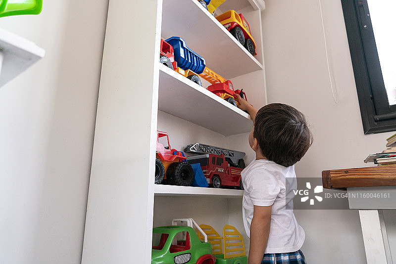 可爱幼儿在家玩玩具卡车图片素材