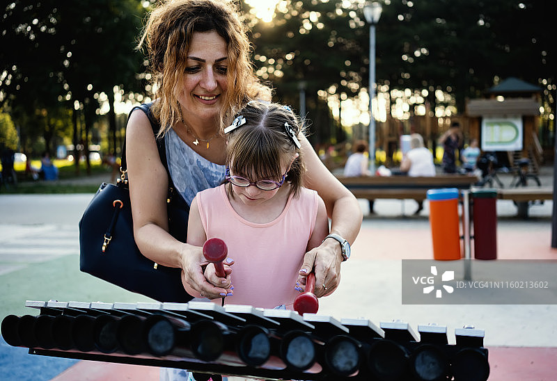 小学生小女孩和母亲在音乐公园玩耍图片素材