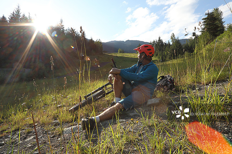 山地自行车手在阿尔卑斯山草甸放松身心，日出美景图片素材