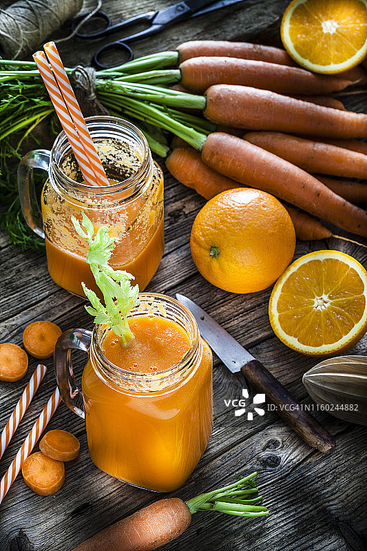 健康饮品：乡村木桌上的橙子和胡萝卜汁图片素材
