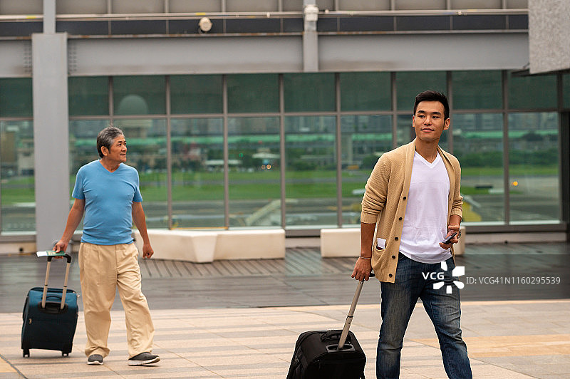 在机场外拿着行李行走的男人图片素材