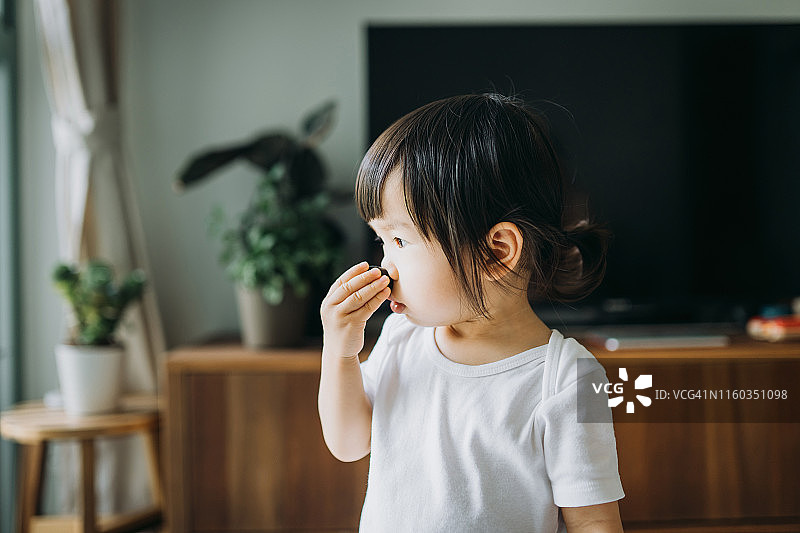 可爱亚洲小女孩在家中客厅吃蓝莓图片素材