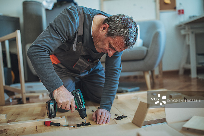 使用无线螺丝刀的年长工匠图片素材